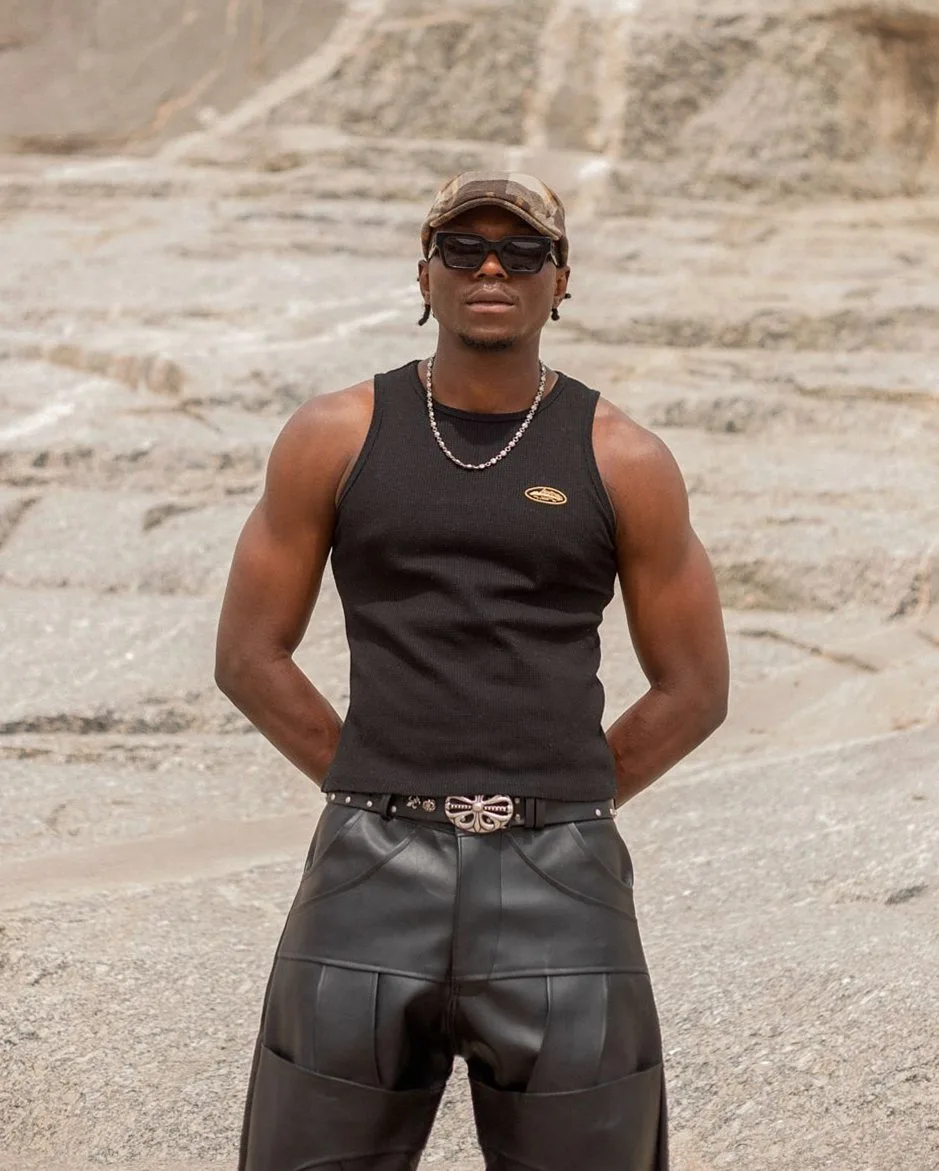 Man in a black sleeveless top and black leather trousers with a studded belt