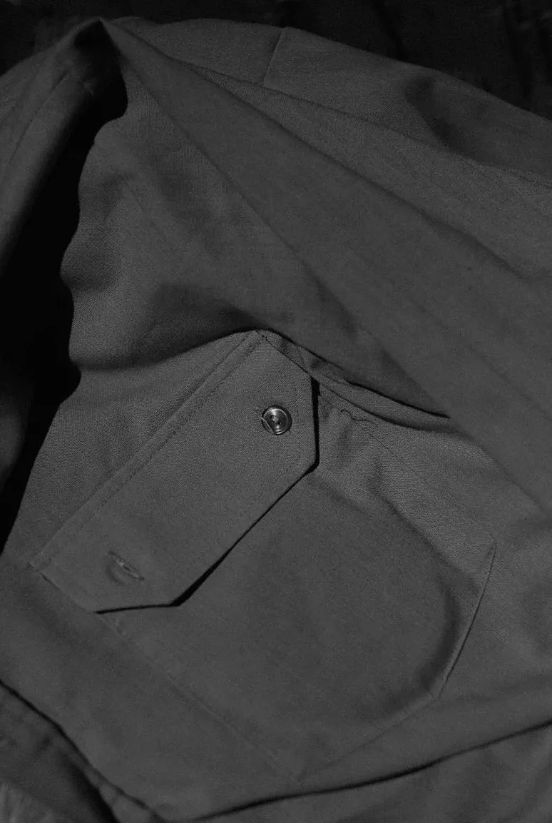 Close-up of a dark charcoal garment with a buttoned flap pocket
