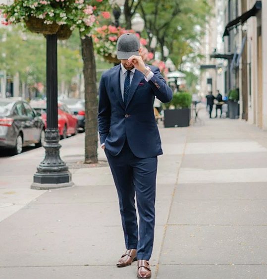 Man in a navy suit and cap walking along a city street